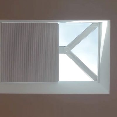 Motorised roof blind in white partially drawn in a skylight