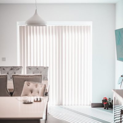 Motorised cream vertical blinds covering sliding glass door in a modern dining room