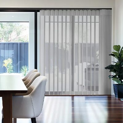 Allusion vertical blinds covering sliding glass doors in a sunlit dining area with upholstered chairs